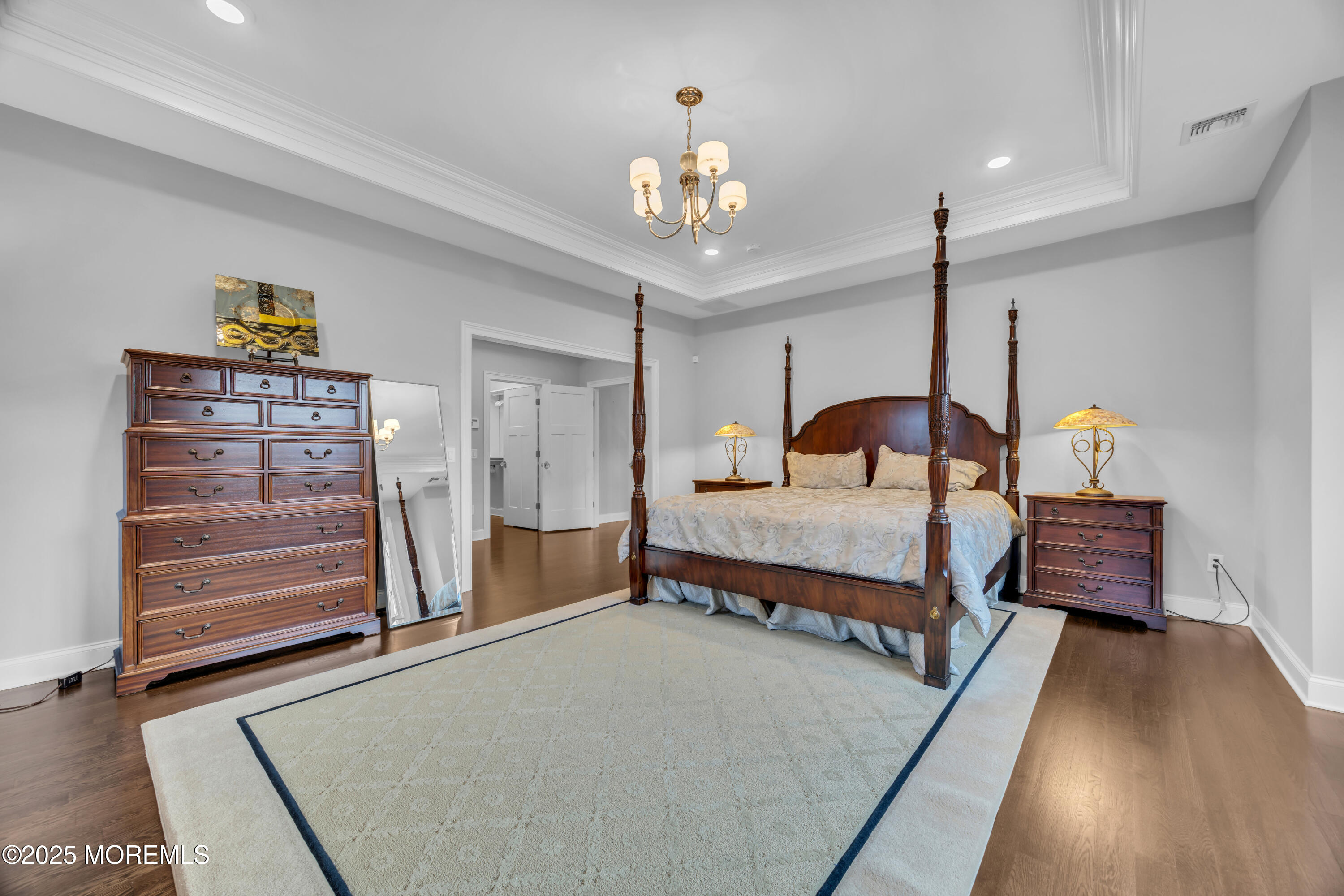 145 Heulitt Road Colts Neck, NJ 07722 - Photo 42 of 59 a bedroom with a bed a chandelier and dresser