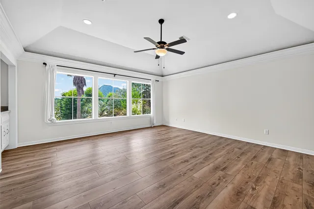 a view of empty room with wooden floor and ceiling fan