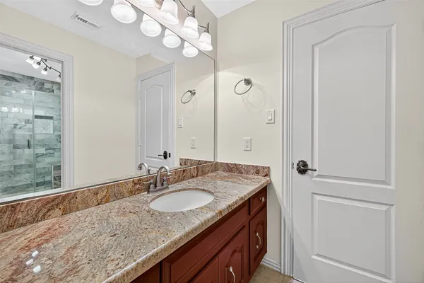 a bathroom with a granite countertop sink a mirror and a shower