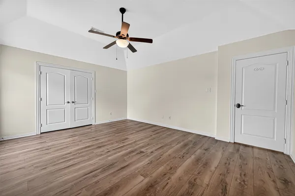 a view of empty room with wooden floor and ceiling fan