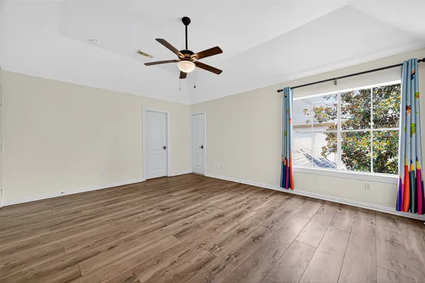 a view of empty room with wooden floor and fan