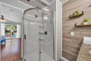 a bathroom with a glass shower door and a wooden floor