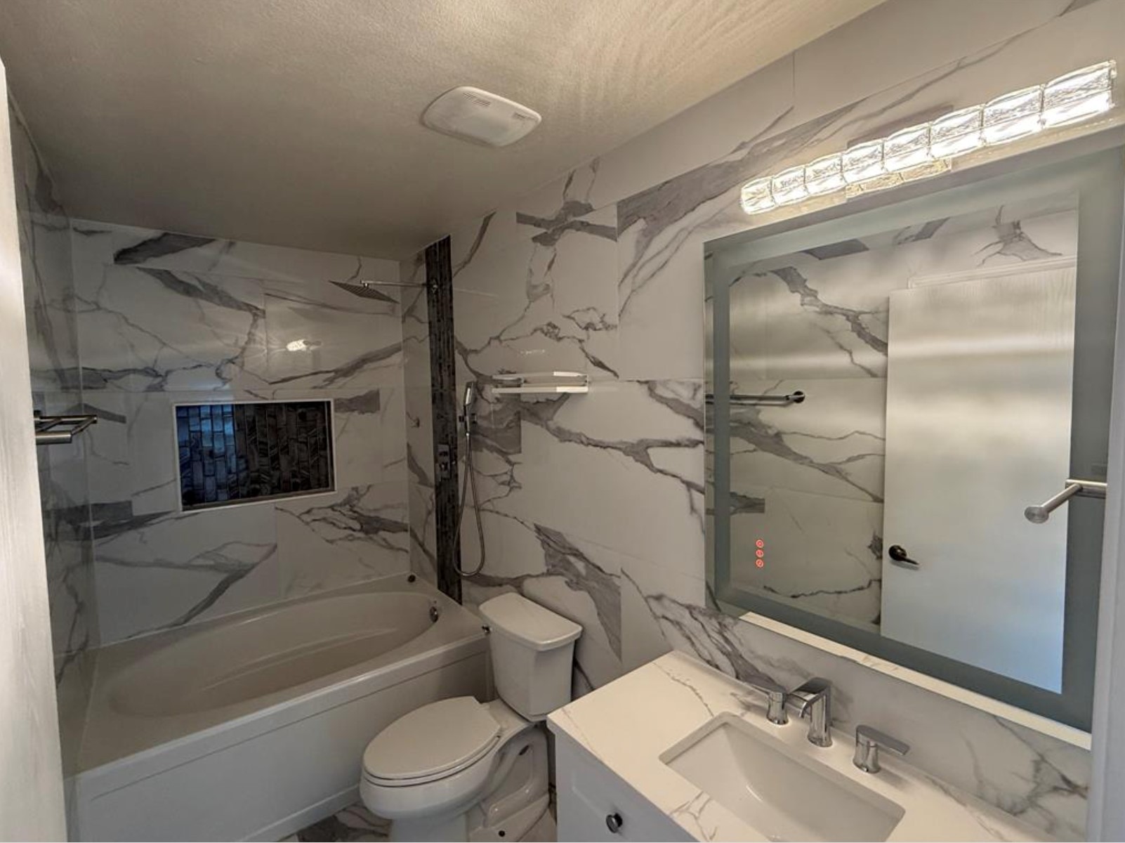 6600 Glebe Path Austin, TX 78754 - Photo 10 of 11 A well-appointed bathroom with striking marble-patterned tile, a bathtub, and a sleek vanity.