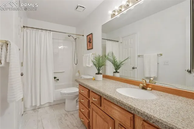 a bathroom with a granite countertop sink a toilet and a large mirror