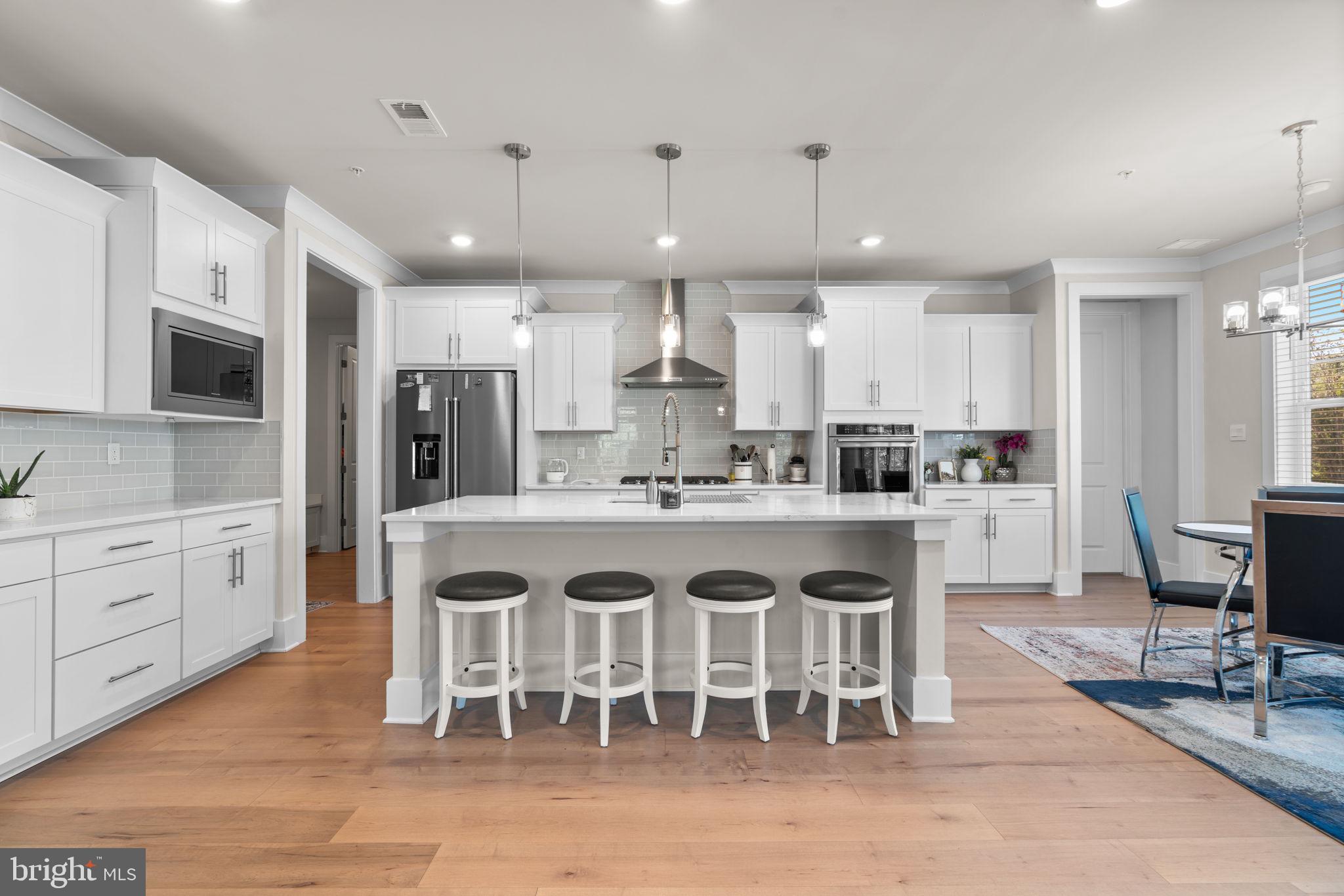 21708 Woodfield Road Gaithersburg, MD 20882 - Photo 5 of 76 a large kitchen with kitchen island a dining table and chairs