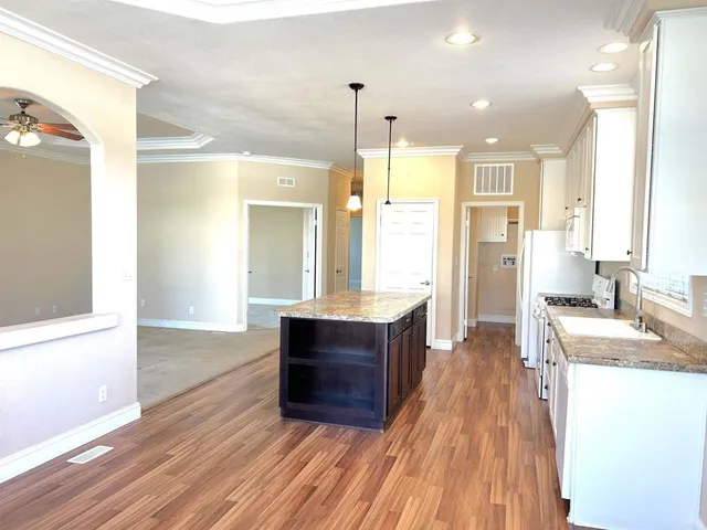 a large kitchen with granite countertop a large counter top a sink stainless steel appliances and cabinets