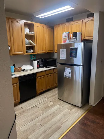 a kitchen with stainless steel appliances granite countertop a refrigerator a sink dishwasher a stove with wooden cabinets and floor