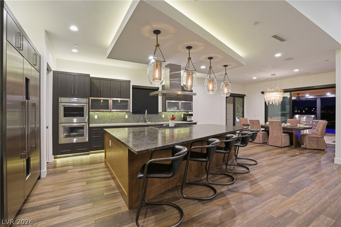 2224 Ledge Rock Lane Henderson, NV 89052 - Photo 15 of 66 Elevated gourmet kitchen with accent lighting, oversized leathered granite island, Thermador appliances, mosaic tile backsplash, double oven, and seamless indoor outdoor living