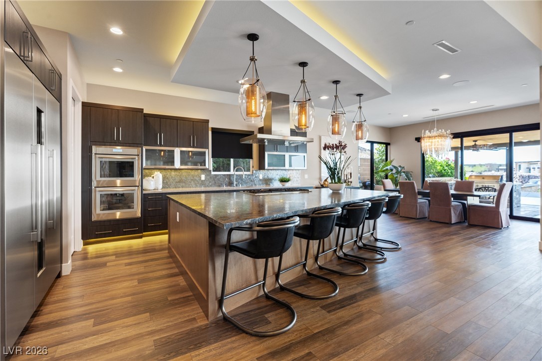 2224 Ledge Rock Lane Henderson, NV 89052 - Photo 18 of 66 Elevated gourmet kitchen with accents lighting, oversized leathered granite island, Thermador appliances, mosaic tile backsplash, double oven, and seamless indoor outdoor living