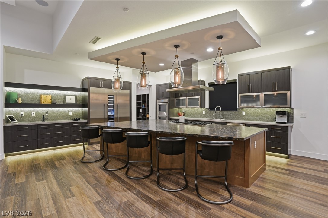 2224 Ledge Rock Lane Henderson, NV 89052 - Photo 20 of 66 Elevated gourmet kitchen with accents lighting, oversized leathered granite island, Thermador appliances, mosaic tile backsplash, double oven, and seamless indoor outdoor living