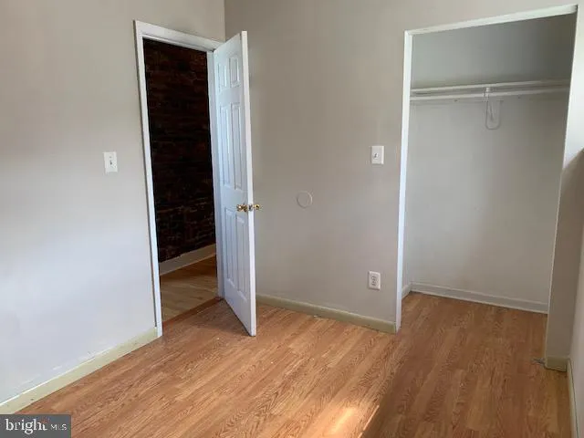 a view of an empty room with wooden floor and closet