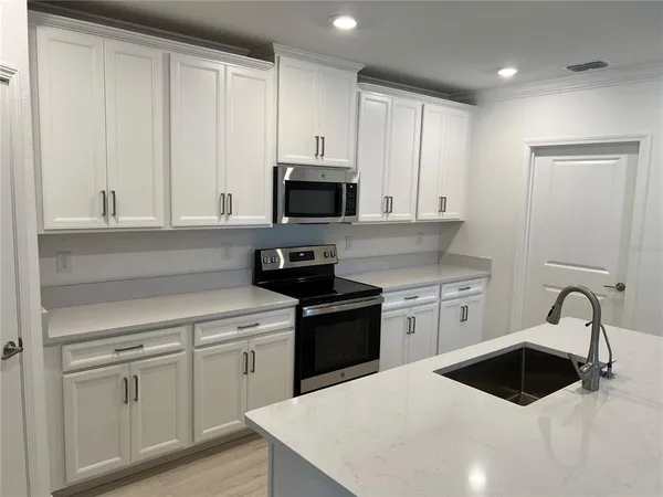 a kitchen with white cabinets and appliances