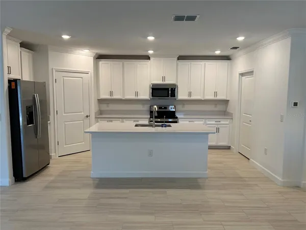 a large kitchen with stainless steel appliances granite countertop a stove a refrigerator a sink and a microwave