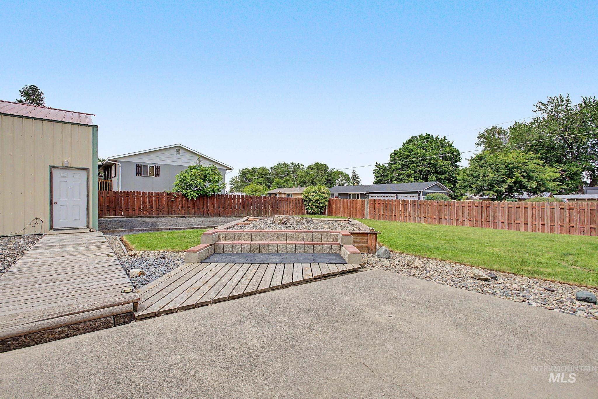 3314 6th Street Lewiston, ID 83501 - Photo 47 of 50 Expansive backyard featuring a concrete patio, wood-finish decking, and a raised garden bed with stone block retaining walls