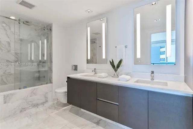 a bathroom with a double vanity sink toilet and shower