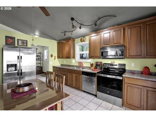 a kitchen with stainless steel appliances kitchen island granite countertop a sink dishwasher stove and refrigerator