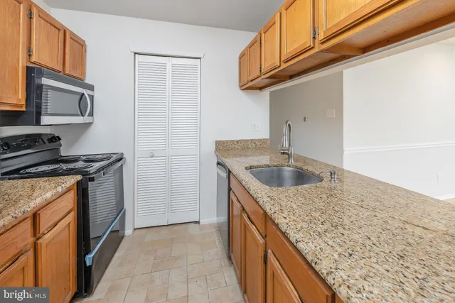 a kitchen with granite countertop a sink stove and cabinets