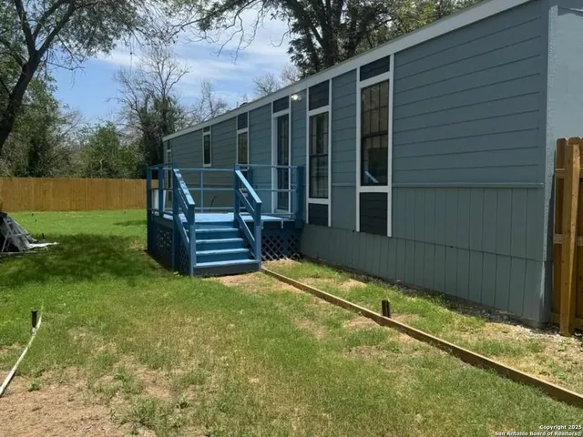 a view of a backyard with wooden fence and a bench