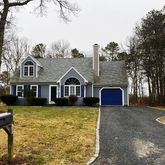 a view of a house with a yard and large trees