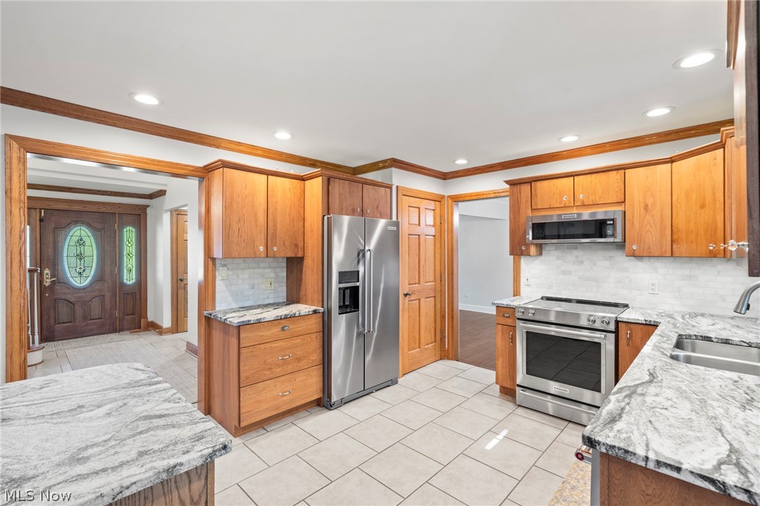 3871 Greentree Road Stow, OH 44224 - Photo 12 of 50 Kitchen with white tile flooring, wood cabinetry, stone countertops, stainless steel appliances, and a tile backsplash