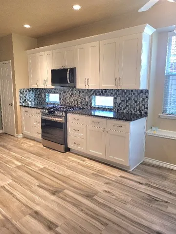 a kitchen with granite countertop a stove and cabinets