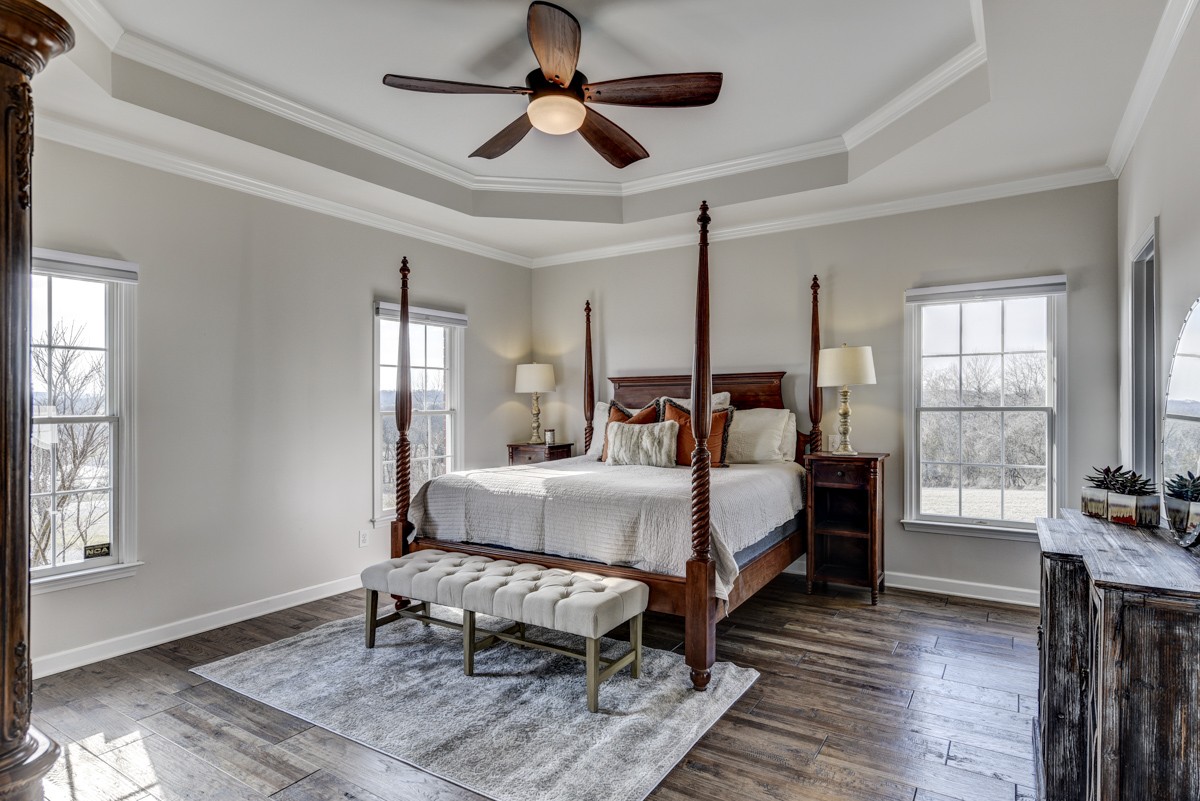 Primary bedroom with trey ceiling and hardwood flooring