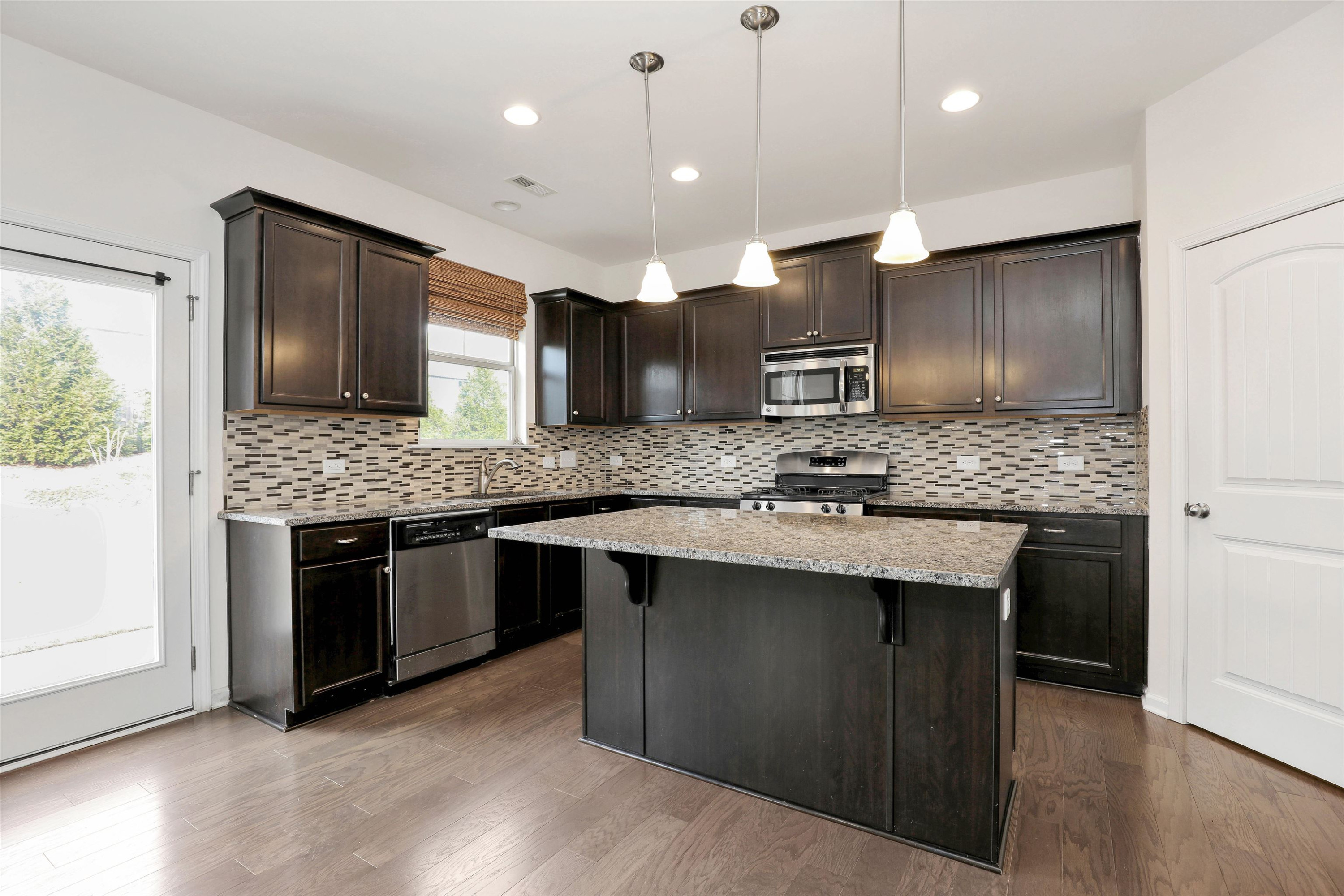 3413 Flat River Drive Durham, NC 27703 - Photo 11 of 40 a kitchen with stainless steel appliances granite countertop wooden cabinets a stove a sink and a large window