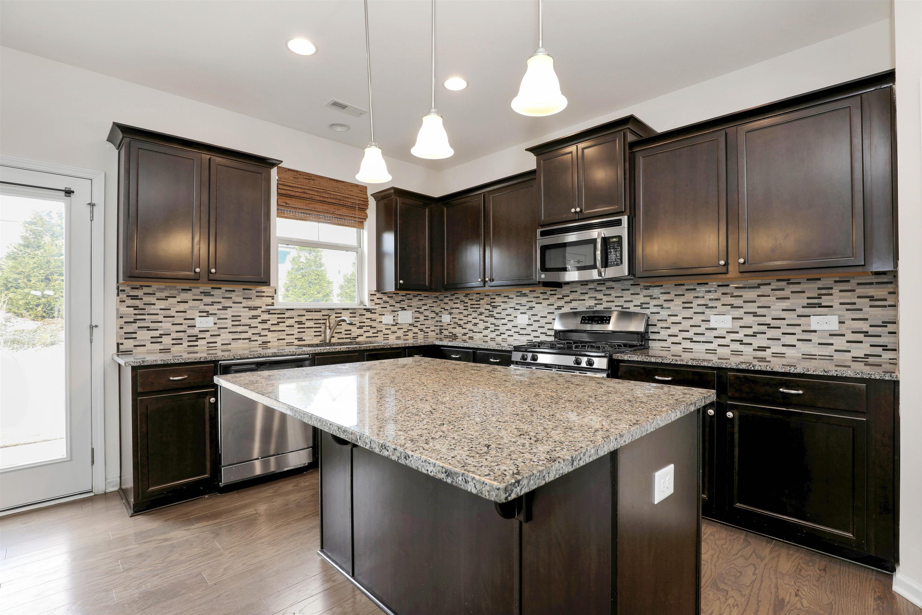 3413 Flat River Drive Durham, NC 27703 - Photo 12 of 40 a kitchen with stainless steel appliances granite countertop a sink stove and microwave