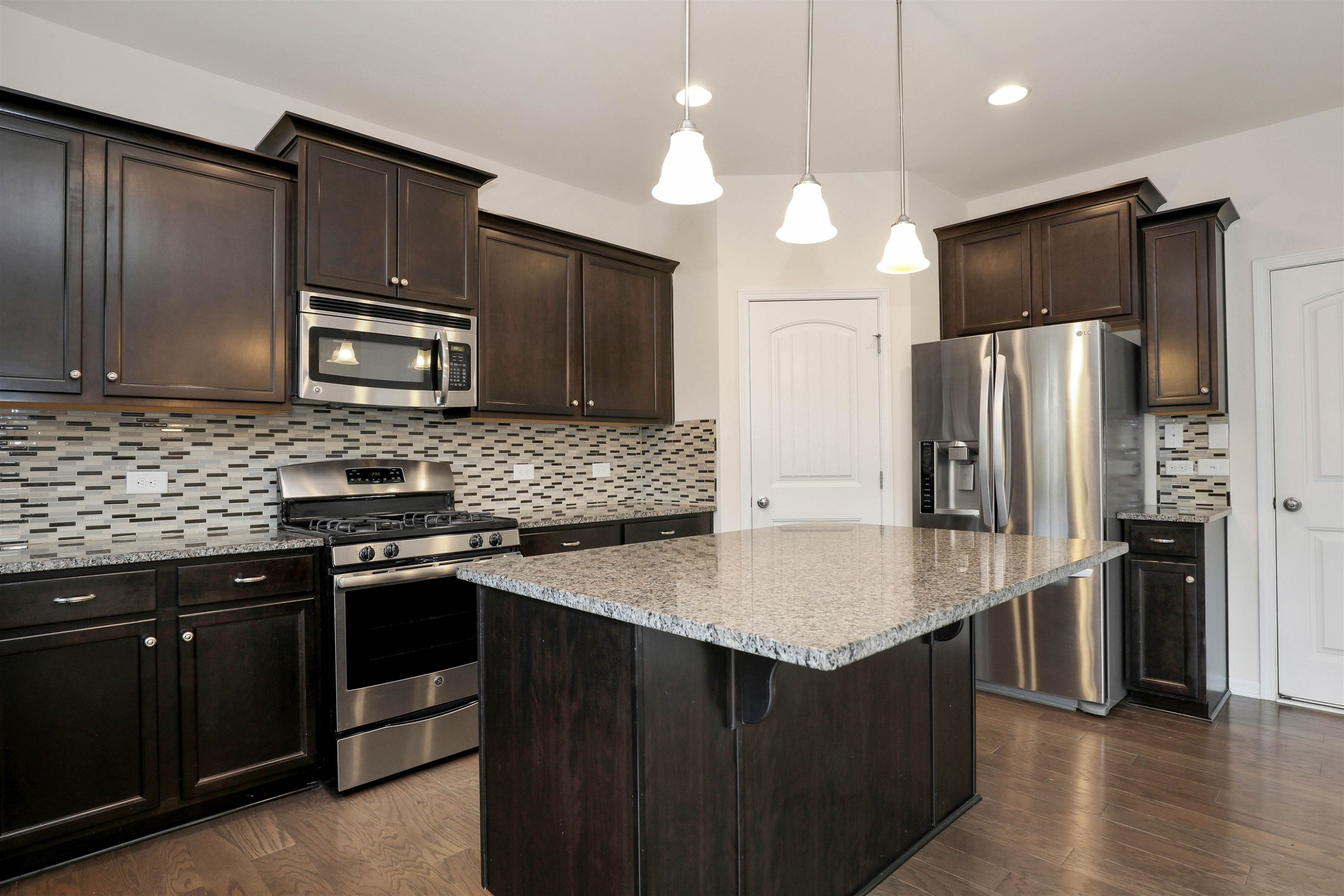 3413 Flat River Drive Durham, NC 27703 - Photo 13 of 40 a kitchen with stainless steel appliances granite countertop a refrigerator a stove a sink and a microwave