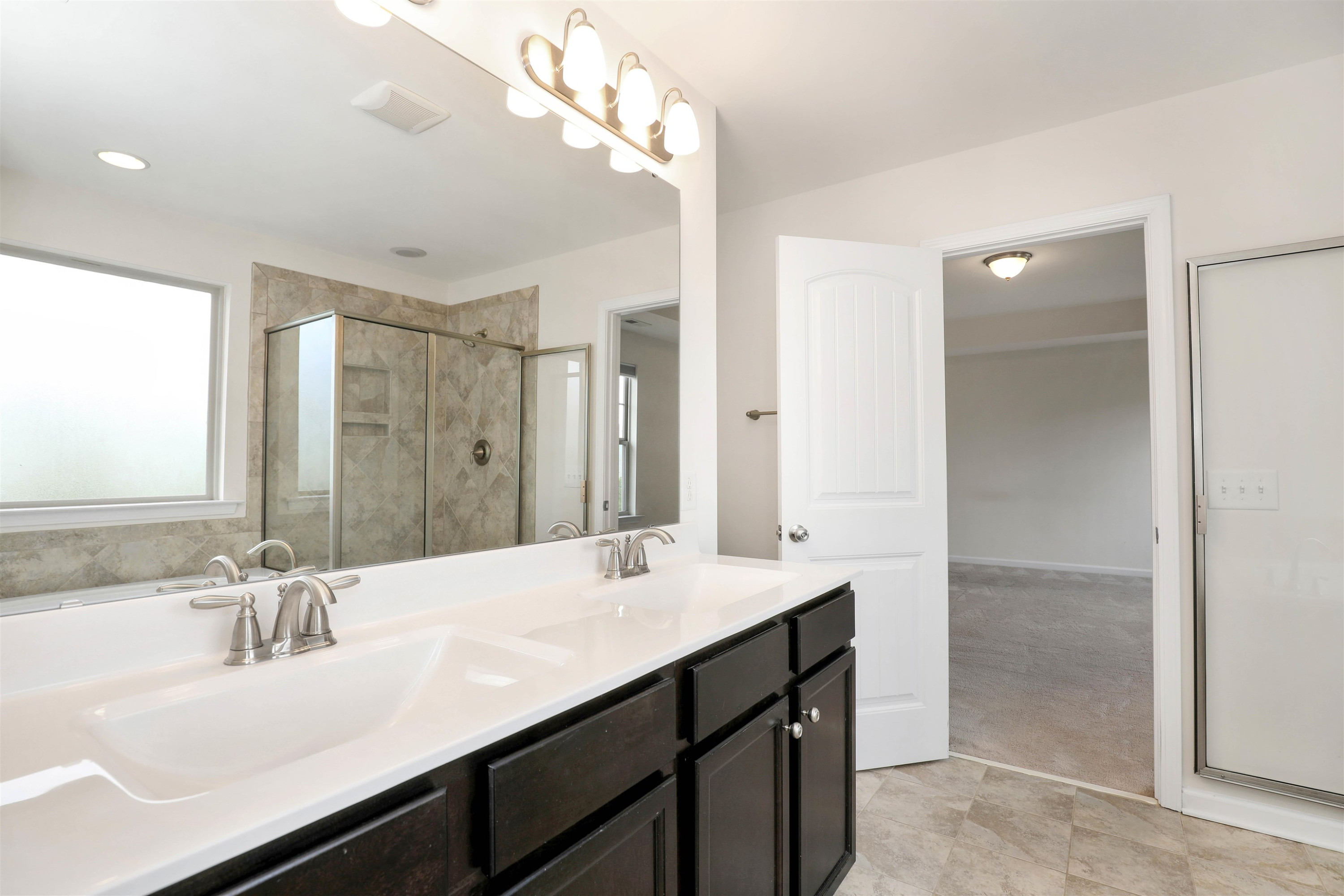 3413 Flat River Drive Durham, NC 27703 - Photo 25 of 40 a bathroom with a double vanity sink a mirror and a shower