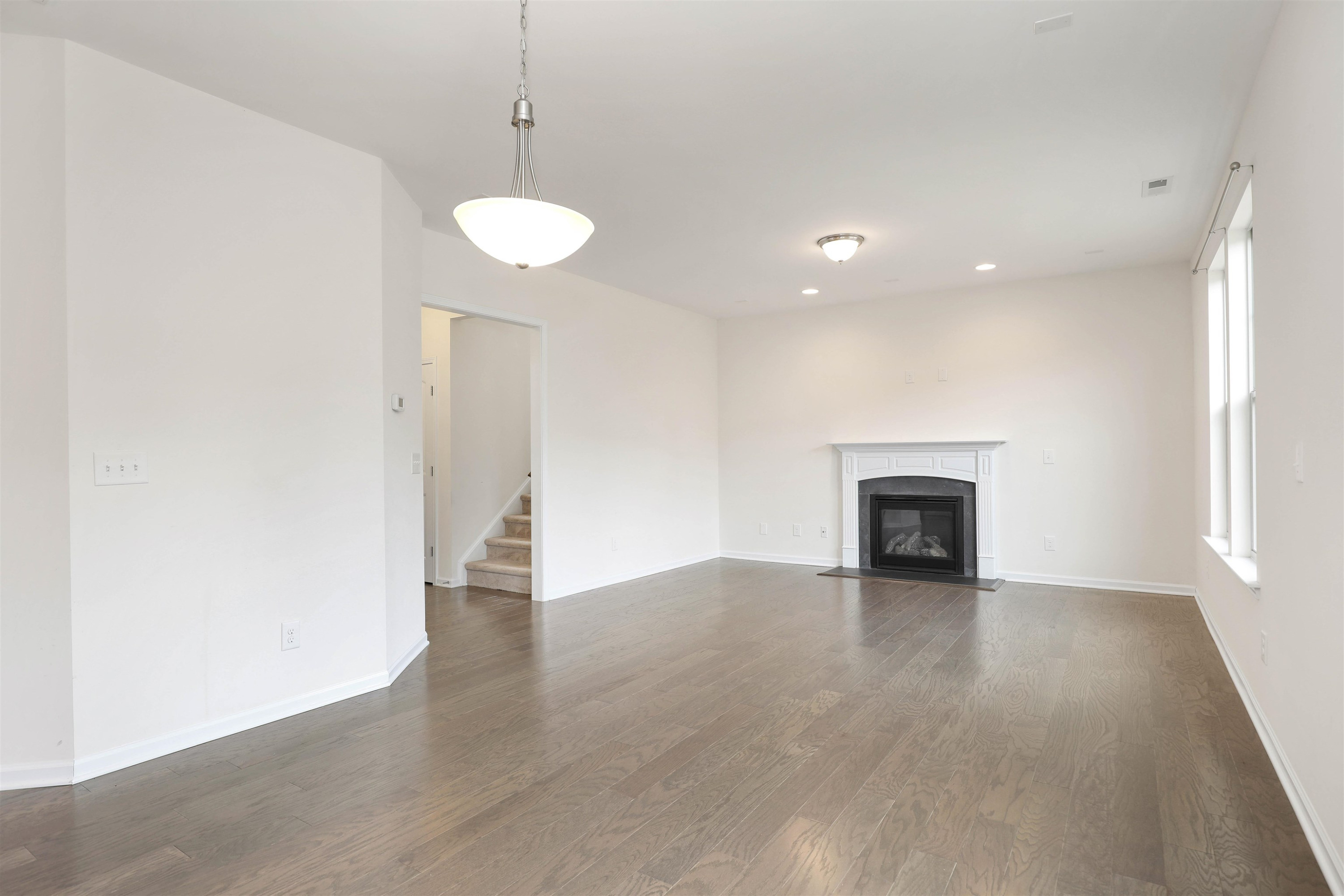 3413 Flat River Drive Durham, NC 27703 - Photo 9 of 40 an empty room with wooden floor and a fireplace