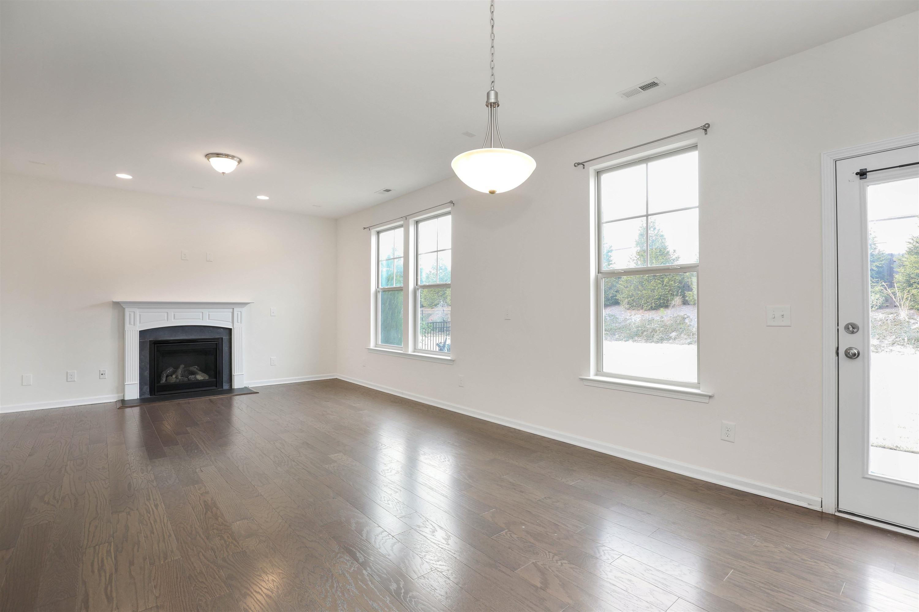 3413 Flat River Drive Durham, NC 27703 - Photo 10 of 40 an empty room with wooden floor chandelier and windows