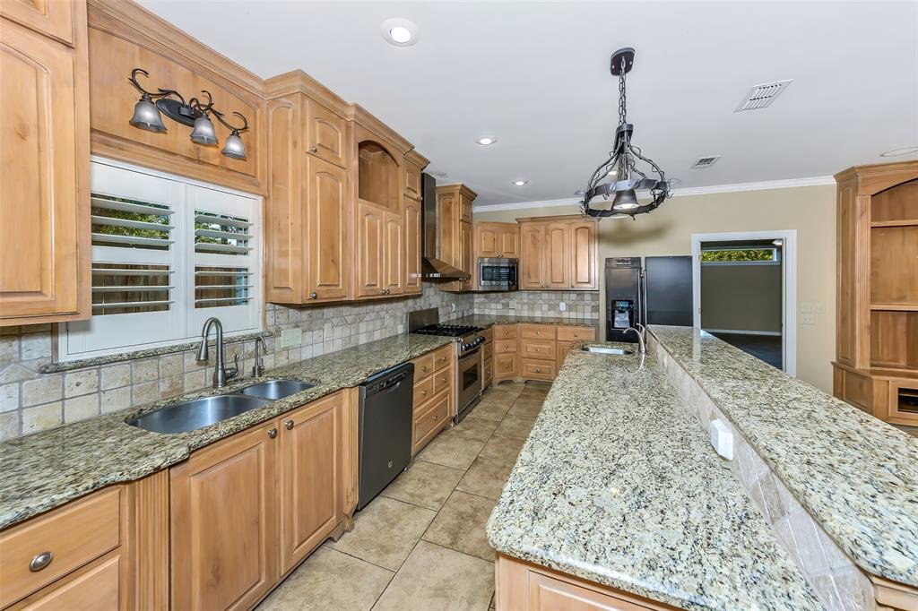 566 Selma Park Road Bowie, TX 76230 - Photo 10 of 40 Kitchen featuring natural wood cabinetry, granite countertops, tile flooring, stainless steel appliances, and a breakfast bar