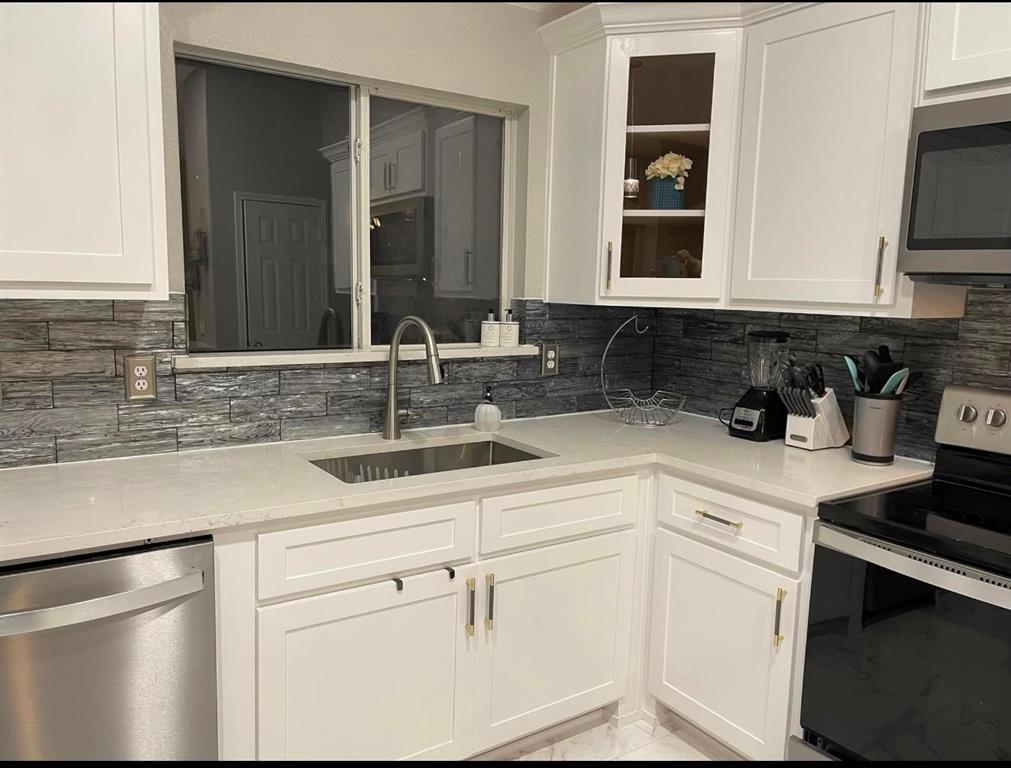 a kitchen with white cabinets and sink