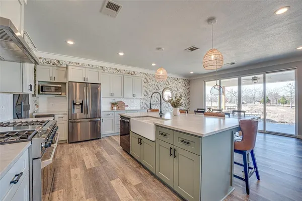 a kitchen with stainless steel appliances a sink a stove a refrigerator cabinets and a large window