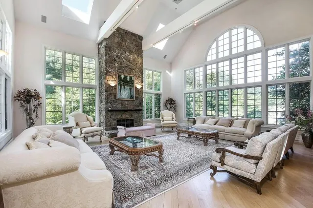 a living room with furniture large windows and wooden floor