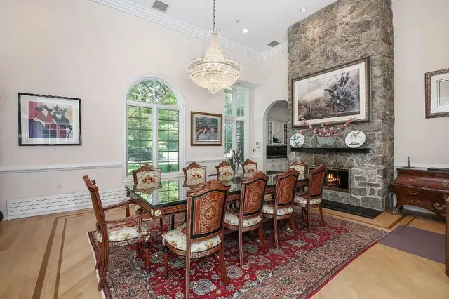 a dining room with wooden floor a chandelier a wooden table and chairs