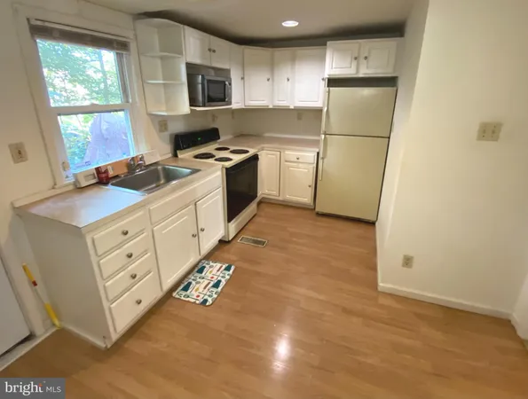 a kitchen with white cabinets and white appliances