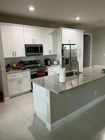 a kitchen with kitchen island granite countertop a sink a counter top space stainless steel appliances and cabinets