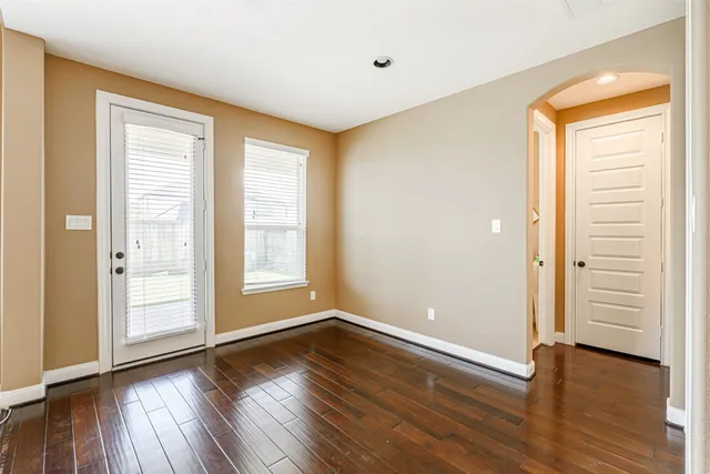 a view of an empty room with a fireplace and a kitchen view