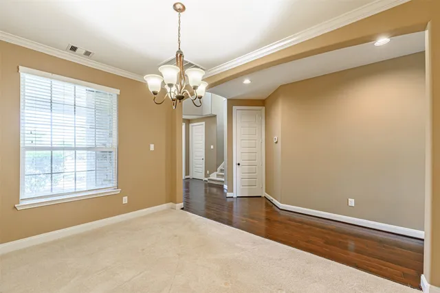 an empty room with wooden floor chandelier and windows
