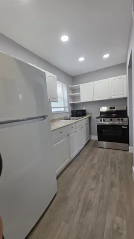 a kitchen with stainless steel appliances granite countertop a refrigerator a sink dishwasher a stove top oven and a refrigerator with wooden floor