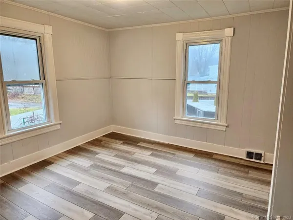 an empty room with wooden floor and windows