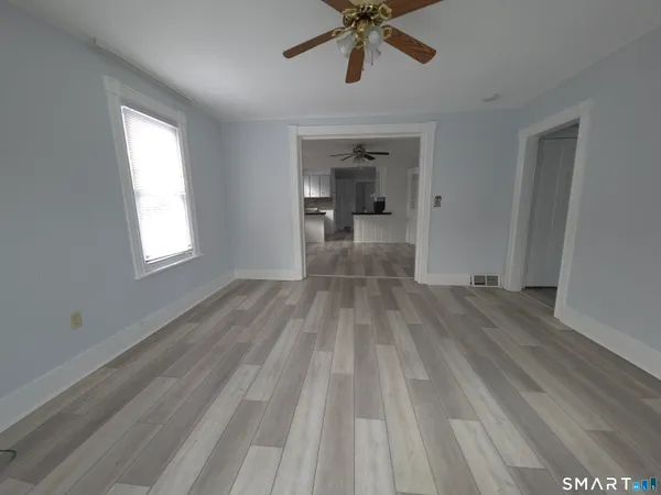 a view of a room with wooden floor ceiling fan and window