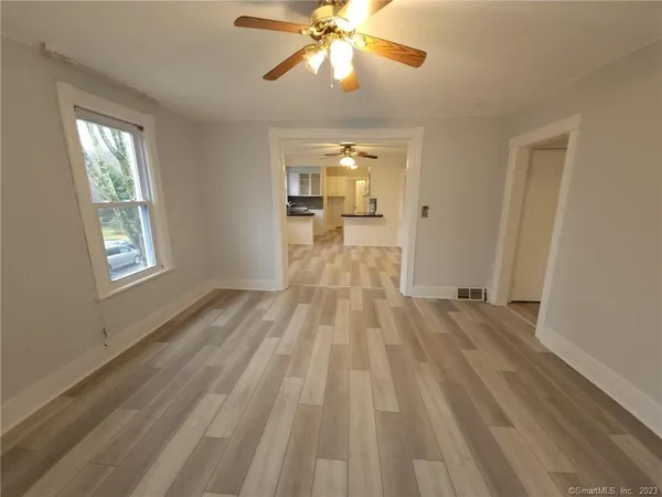 a view of a room with wooden floor fan and windows
