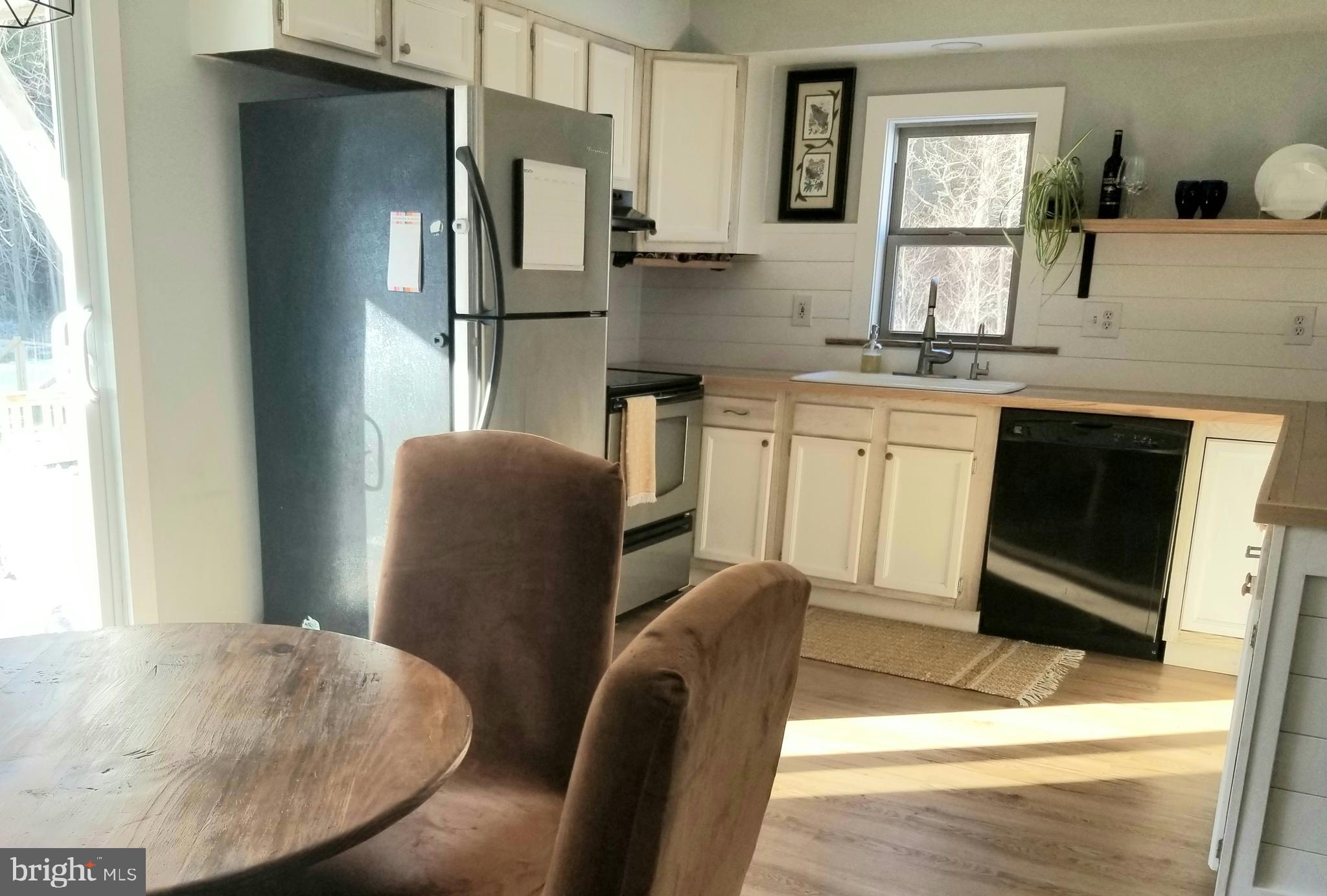 7741 Downs Road Newark, MD 21841 - Photo 10 of 22 a kitchen with stainless steel appliances granite countertop a refrigerator a stove a sink a dining table and chairs