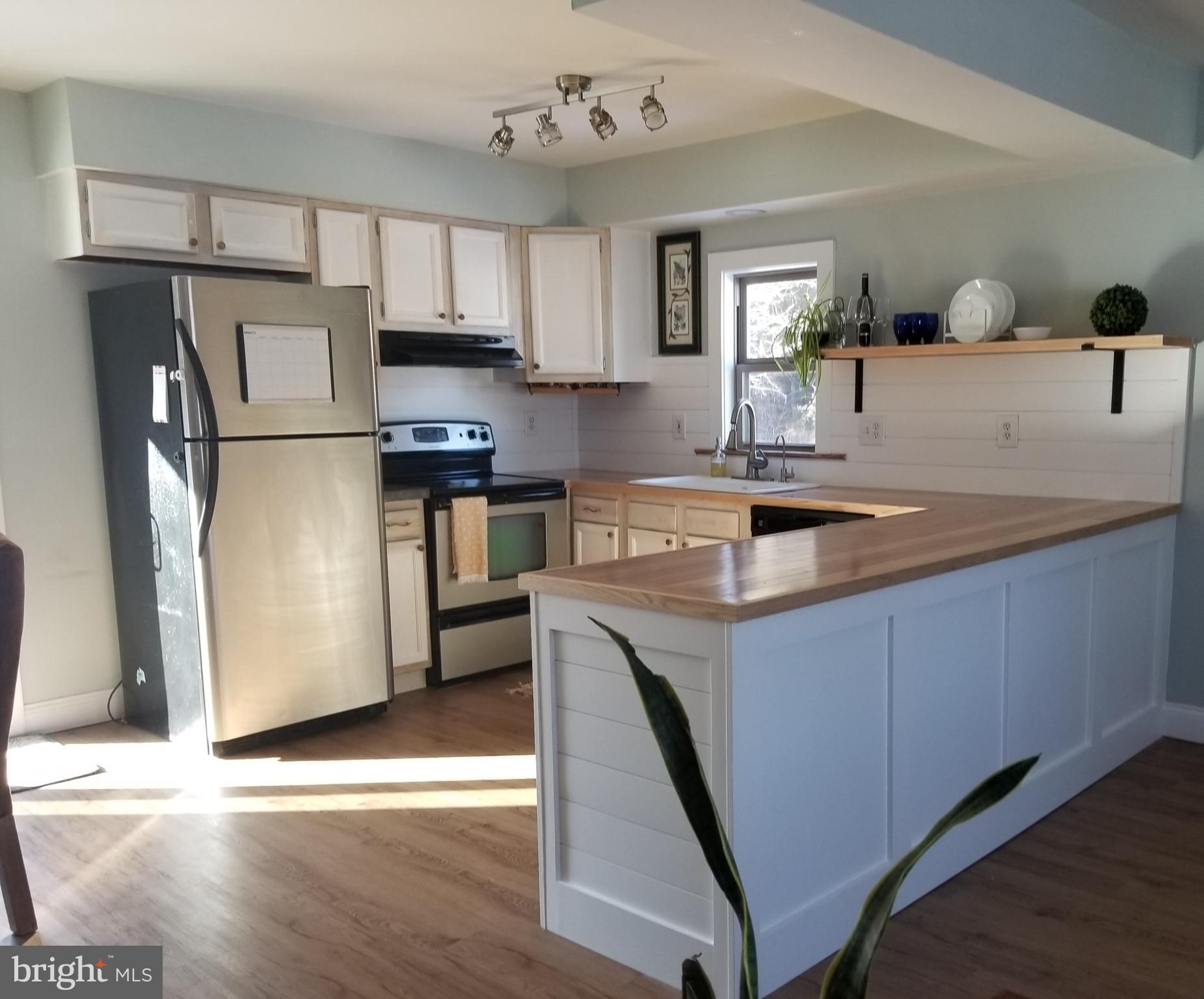 7741 Downs Road Newark, MD 21841 - Photo 8 of 22 a kitchen with stainless steel appliances granite countertop a refrigerator a sink dishwasher a stove and white countertops with wooden floor