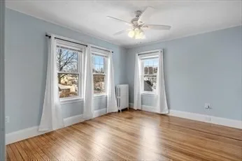 an empty room with wooden floor cabinet and windows