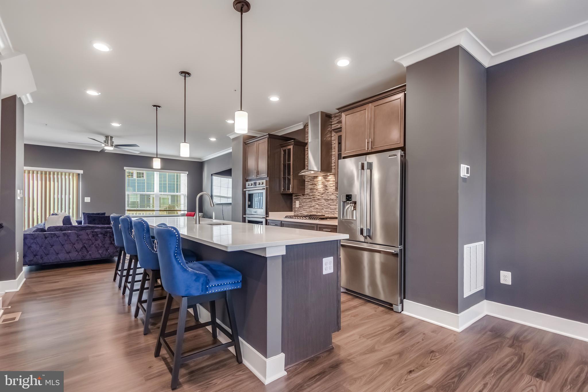 7806 Johnnycake Road Windsor Mill, MD 21244 - Photo 10 of 28 a kitchen with stainless steel appliances granite countertop a refrigerator a stove a sink dishwasher and a dining table with wooden floor