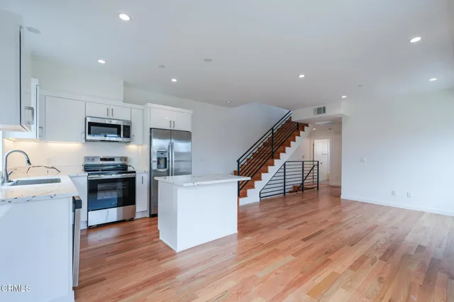 a kitchen with wooden floors and stainless steel appliances